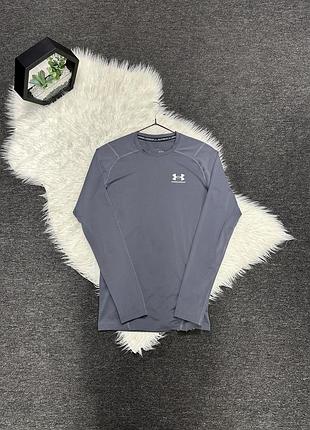 Сірий компресійний лонгслів under armour hg armour comp ls із фірмовим білим логотипом бренду на грудях.
