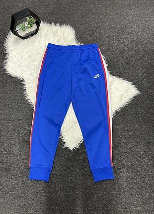 Сині спортивні штани nike m nsw he jggr pk tribute (модель ar2255-480) із білими та червоними бічними смужками.