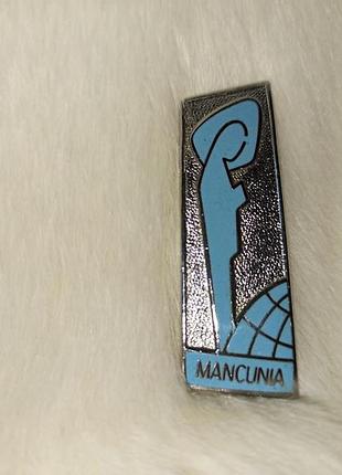 Вінтажний металевий значок прямокутної форми з написом mancunia великобританія манчестер і зображення земної кулі з силуетом фігури