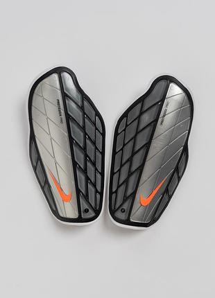 Футбольні щитки nike protegga attack premium з виразним, спортивним дизайном у чорно- сріблястому кольорі. передня частина має рельєфну конструкц