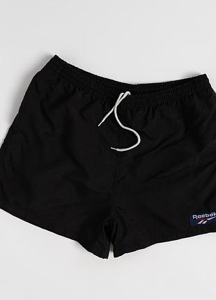 Чоловічі, вінтажні шорти reebok чорного кольору, виконані з легкої, нейлонової тканини. модель має еластичний пояс із регульованим шнурком,