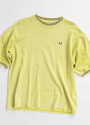 Чоловіча, вінтажна футболка fred perry у світло-жовтому відтінку з характерним, фірмовим вінком лавра на грудях. модель має цікавий, вінтажний