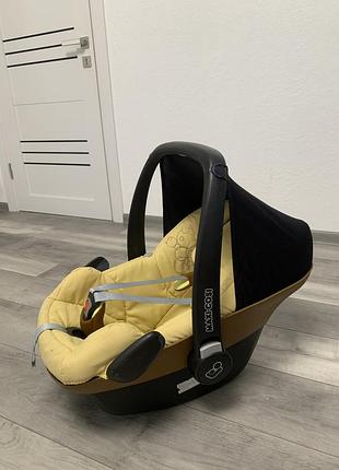 Жовте дитяче автокрісло-переноска (автолюлька) моделі maxi-cosi pebble, призначене для малюків від народження до приблизно 12–15 місяців