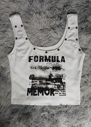 Білий обтислий кроп-топ у рубчик прикрашений принтом «formula» і металевими заклепками.