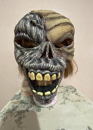 Карнавальна напівмаска (half mask) у формі обличчя зомбі або мумії, призначена для хелловіну, костюмованих вечірок чи тематичних заходів.