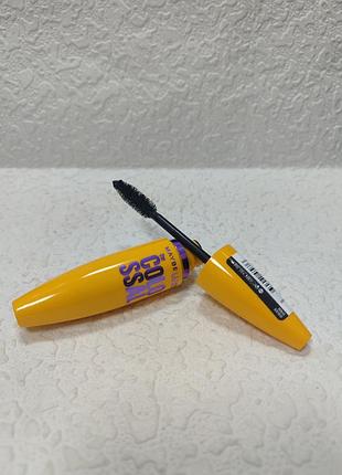 Объемная тушь для ресниц maybelline new york volum' express the colossal в ярко-желтом тюбике с фиолетовым и черными надписями.