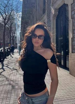 Zara — чорна асиметрична блуза з драпіруванням і металевою деталлю.