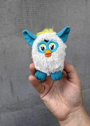 Маленьку м'яку іграшку фербі (furby) білого та блакитного кольорів з жовтим чубчиком, випущену компанією hasbro для mcdonald's happy meal у 2013 році