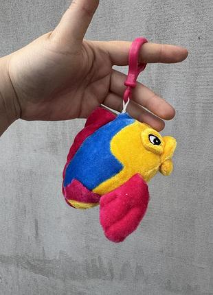 Брелок у вигляді тропічної рибки жовтого, синього та рожевого кольорів із пластиковим рожевим карабіном.