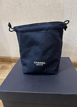 Темно-синій косметичний мішечок-затяжку chanel beauté з білим друкованим логотипом бренду на передній частині.
