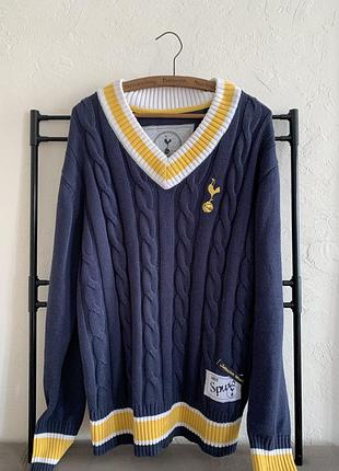 Темно - синій в'язаний светр tottenham hotspur з v-подібним вирізом, прикрашений характерними жовто-білими смужками.