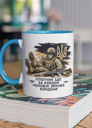 Чашка керамічна з принтом "хлопчик їде за кордон чоловік змінює кордони" 330 мл, біла з блакитною ручкою