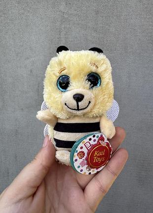 М'яка іграшка-бджілка motsu bumble bee від британського бренду keel toys, яка має характерні блакитні блискучі очі та чорно-жовті смужки.