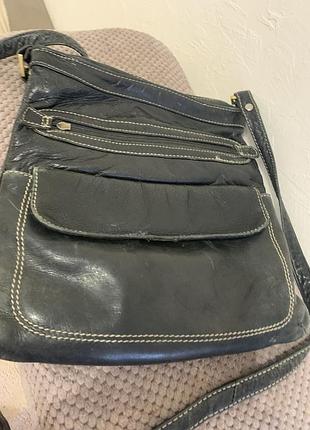Чорна шкіряна сумка через плече (crossbody), яка має передню кишеню з клапаном та відділення на блискавці.