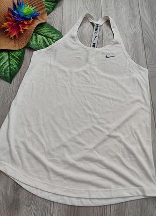 Біла жіноча спортивна майка nike dry essential elastika tank із невеликим чорним логотипом на грудях та еластичною лямкою на спині розмір m