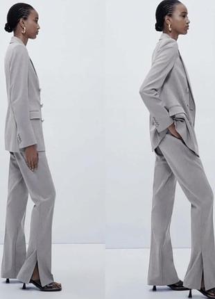 Сірі костюмні штани бренду zara із характерними розрізами (шліцами) внизу штанин