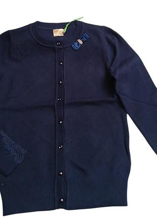 Синий вязаный кардиган для девочки на пуговицах, украшен декоративным бантом у горловины и вышивкой со стразами на манжетах.