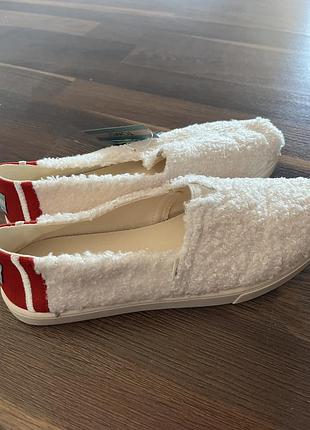 Сліпони toms alpargata cupsole faux shearling з м'яким пухнастим верхом текстури штучної овчини та яскравими червоними акцентами на п'яті.