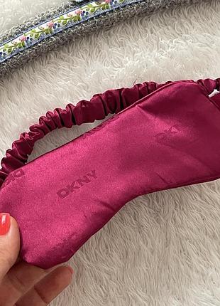 Атласна маска для сну бренду dkny (donna karan new york) з еластичним приспереним ремінцем та витисненим логотипом на тканині.