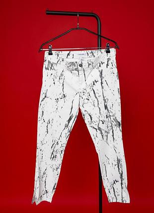Стильні, жіночі брюки calvin klein у білому кольорі з виразним, чорно-сірим, абстрактним принтом, що нагадує мармурові або графічні мазки. незвичайни