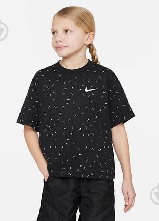 Чорна укорочена футболка nike з принтом у вигляді дрібних білих логотипів swoosh по всій поверхні та великим білим логотипом на грудях.