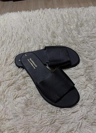 Черные кожаные шлепанцы ручной работы с золотистой надписью «handmade made in greece» на стельке.