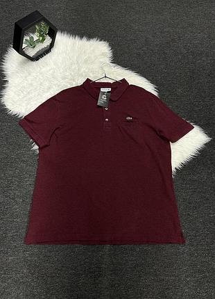 Бордове чоловіче сорочка-поло бренду lacoste з короткими рукавами, коміром на ґудзиках та невеликою кишенею на грудях.