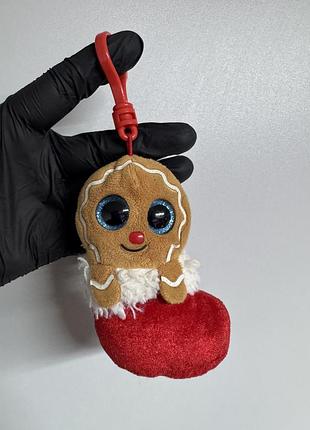 Брелок-кліпса «jingly the gingerbread» від бренду ty приваблює увагу своїми виразними блискучими блакитними очима