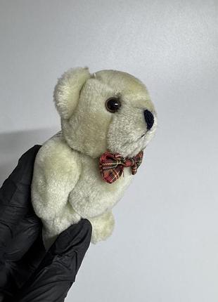 Невеликого плюшевого ведмедика світлого бежевого кольору з червоним клетчастим бантом