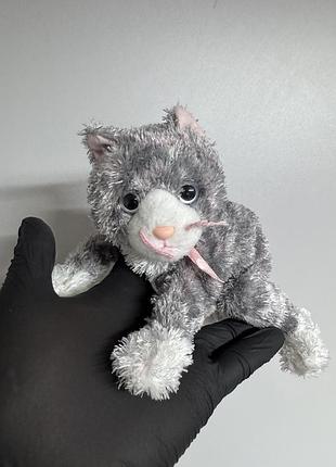 М'яку іграшку aria the cat із серії ty beanie babies, яка має характерне сіре пухнасте хутро, білу мордочку та рожевий бантик-стрічку на шиї