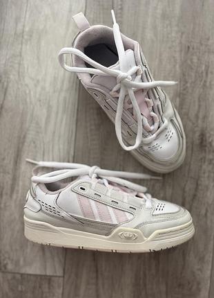 Кросівки adidas adi2000 у біло-рожевому забарвленні, які вирізняються ретро-дизайном у стилі 2000-х років із м'якими велюровими 3-смужками
