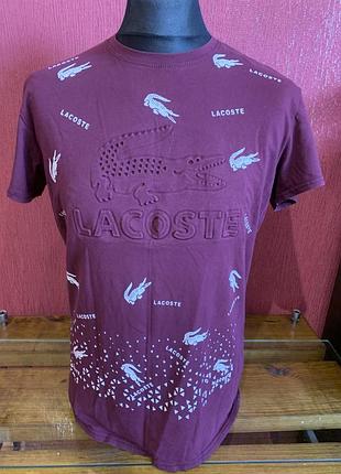 Бордова футболка від бренду lacoste з великим об'ємним тисненням логотипу та написом «lacoste»