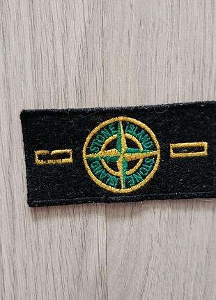 Черный винтажный патч (шеврон) бренда stone island с круглой вышитой эмблемой и двумя прорезями для крепления на пуговицы