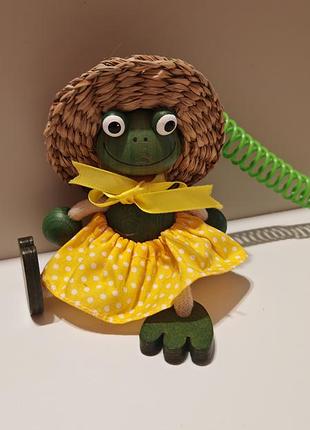Подвесная деревянная игрушка-пружинка (bouncy toy / jumper), похожая на лягушку в соломенной шляпке и желтом платье в горошек