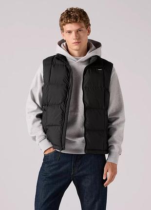 Levi’s жилета в чорному кольорі, з щільного нейлону. утеплена штучним наповнювачем. має стяжки понизу.