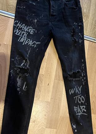 Черные зауженные джинсы zara , рваными деталями на коленях и белым граффити-принтом («change with impact», «way too far»)