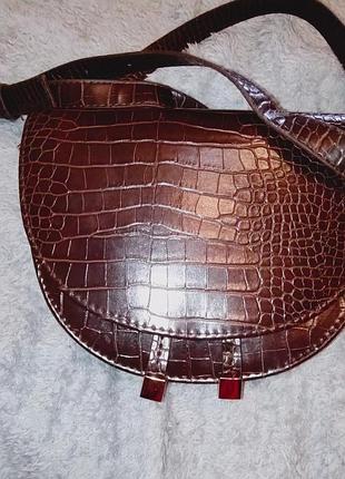 Женская сумка-седло (crossbody) с тиснением под крокодила (или рептилию) и металлической  фурнитурой.