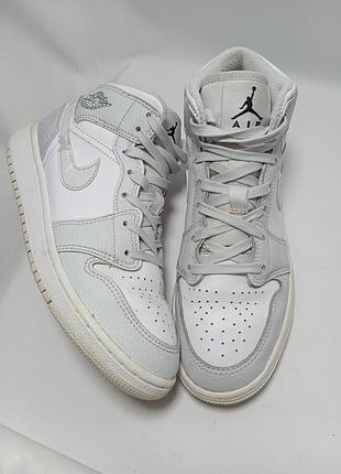 Кросівки nike air jordan 1 mid grey camo (артикул dc9035-100), виконані у біло-сірій гамі з характерним візерунком на логотипі-свуші.