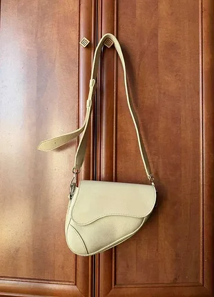 Трендовая женская сумочка формы saddle bag (сумочка-седло) в бежевом оттенке.