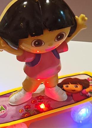 Детская интерактивная игрушка «даша-путешественница» (dora the explorer) на скейтборде с батарейками, которая умеет двигаться, петь и светиться