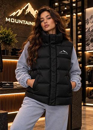Жіноча утеплена жилетка mountains чорна стьобана на біопуху з коміром-стійкою та кнопками (b)
