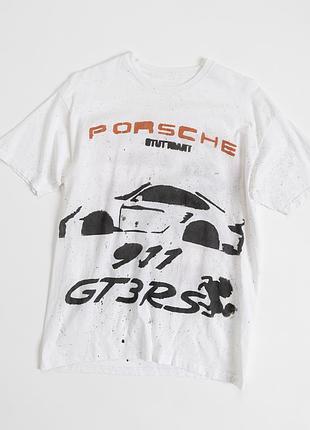 Чоловіча, біла футболка з виразною, вінтажною графікою porsche racing — знахідка для поціновувачів автомобільної культури та автоспорту. спереду розмі