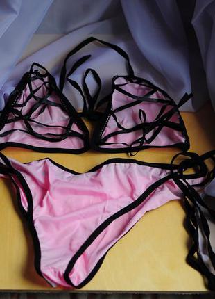 Нежный розовый купальник с черными ленточками и завязками и черной шнуровкой на чашечках чашках