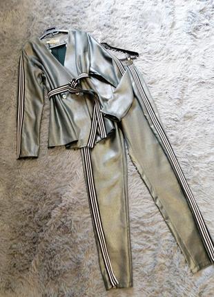 Эффектный брючный костюм из материала с напылением «металлик» состоит из пиджака с пуговицами и зауж