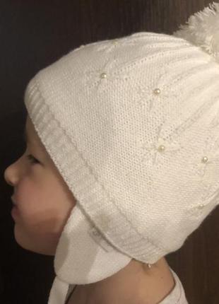Белая детская шапочка с рисунком бубоном ушками