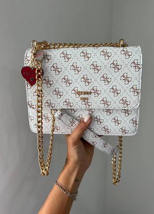 Розкішна біла брендова сумка в стилі guess з ланцюжком і сердечком сумка біла з золотим ланцюжком з червоною підкладкою всередині1 фото