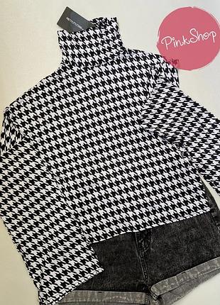 Трикотажна блуза монохромного кольору з крутимо горлом та широкими рукавами.