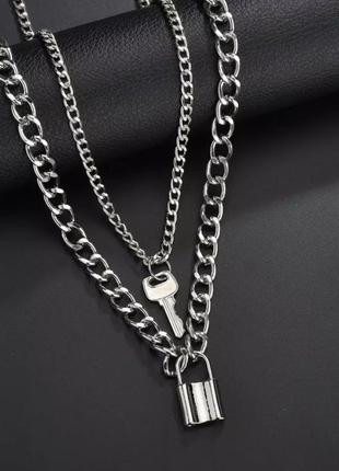 Многослойное ожерелье- цепочка с подвесками в форме замка и ключа в серебряном цвете.
