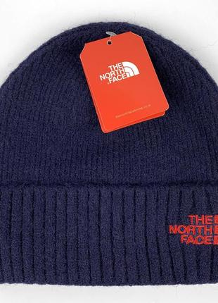 Зимова шапка the north face, колір темно-синій з червоним логотипом