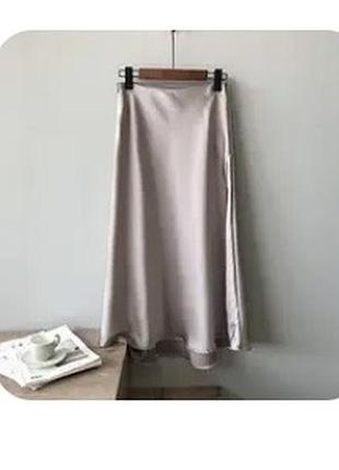 Атласна спідниця міді (slip skirt) перлинно-бежевого відтінку з делікатним сатиновим переливом, злегка розширена донизу (крій по косій).